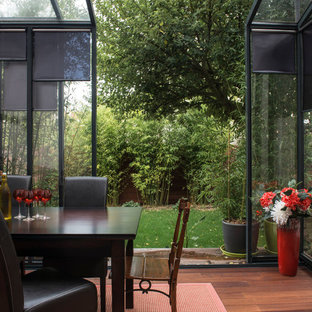 Idée de décoration pour une véranda design de taille moyenne avec un sol en bois brun, aucune cheminée et un plafond en verre.