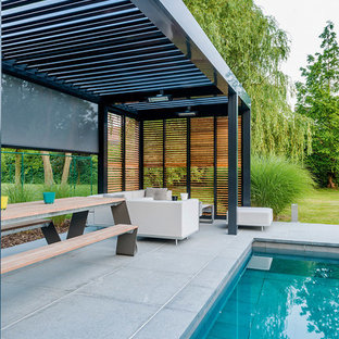 Ispirazione per un grande portico design dietro casa con un portico chiuso, piastrelle e una pergola