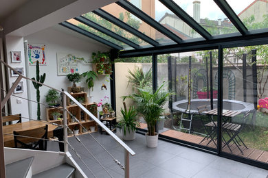 Modelo de galería contemporánea de tamaño medio con estufa de leña, techo de vidrio y suelo gris