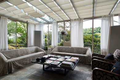Esempio di una grande veranda design con pavimento in pietra calcarea, soffitto in vetro e pavimento grigio