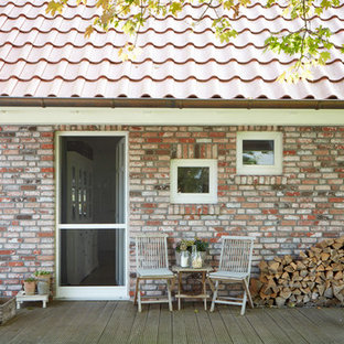 Mittelgroße, Überdachte Landhaus Veranda neben dem Haus mit Kübelpflanzen und Dielen in Bremen