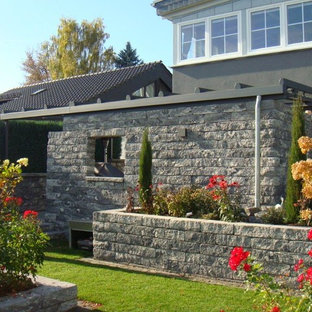 Immagine di un portico country di medie dimensioni e dietro casa con pavimentazioni in pietra naturale e un parasole