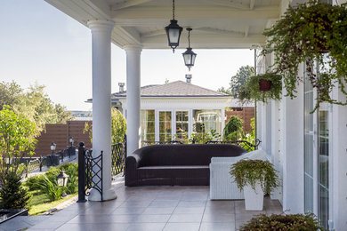 Modelo de terraza clásica de tamaño medio en patio trasero y anexo de casas con adoquines de piedra natural y jardín de macetas