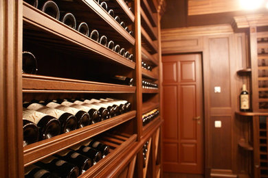 Photo of a medium sized classic wine cellar in Moscow with dark hardwood flooring and storage racks.