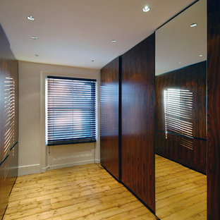 Ispirazione per una grande cabina armadio unisex design con ante lisce, ante in legno bruno e parquet chiaro