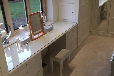 Design ideas for a large modern dressing room for women in Gloucestershire with shaker cabinets, white cabinets, carpet and beige floors.