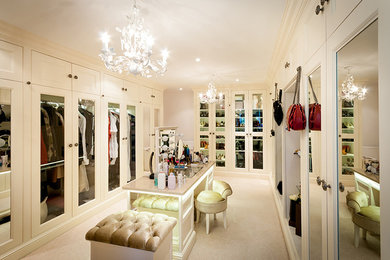 This is an example of an expansive classic dressing room for women in Surrey with white cabinets and carpet.