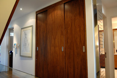 Photo of a medium sized contemporary wardrobe in London with flat-panel cabinets and dark wood cabinets.