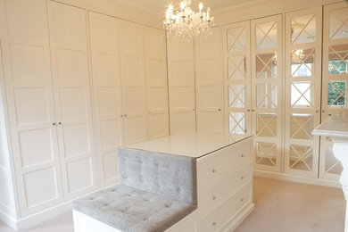 Inspiration for a large traditional walk-in wardrobe in London with white cabinets, carpet and beige floors.