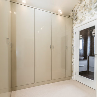 Imagen de vestidor de mujer, actual, grande, con armarios con paneles lisos, puertas de armario beige, moqueta y suelo beige