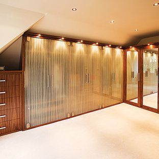 Foto de armario vestidor unisex, ecléctico, de tamaño medio, con armarios tipo vitrina, puertas de armario de madera oscura, moqueta y suelo beige