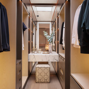 Idee per uno spazio per vestirsi unisex contemporaneo di medie dimensioni con ante marroni, parquet chiaro e nessun'anta