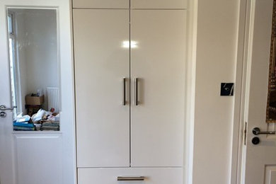 Imagen de armario unisex minimalista pequeño con armarios con paneles lisos, puertas de armario blancas y suelo de madera clara