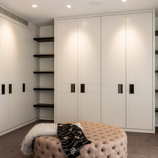 Inredning av ett klassiskt stort walk-in-closet för könsneutrala, med släta luckor, vita skåp, heltäckningsmatta och brunt golv