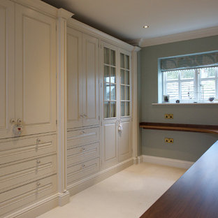 Modelo de vestidor de mujer, de estilo de casa de campo, grande, con armarios estilo shaker, puertas de armario beige y moqueta