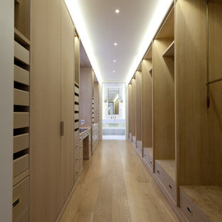 Modelo de armario vestidor minimalista, grande, con puertas de armario de madera clara y suelo de madera clara