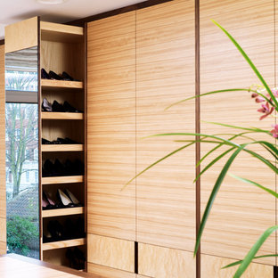 Diseño de armario vestidor unisex, moderno, grande, con armarios con paneles lisos, moqueta y puertas de armario de madera clara