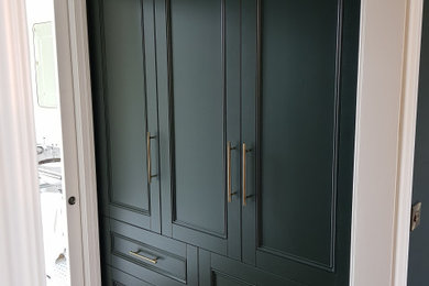 Ejemplo de vestidor unisex clásico de tamaño medio con armarios con paneles empotrados, puertas de armario verdes, suelo de madera en tonos medios y suelo marrón