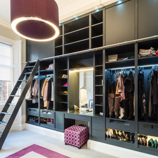 Photo of a contemporary dressing room for women in Glasgow with open cabinets, black cabinets, carpet and beige floors.