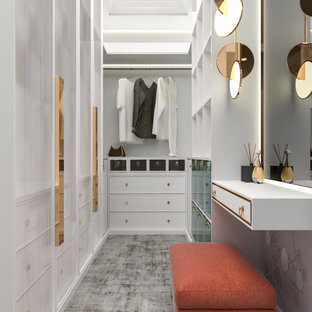 Immagine di una piccola cabina armadio per donna moderna con ante di vetro, ante in legno chiaro e pavimento grigio