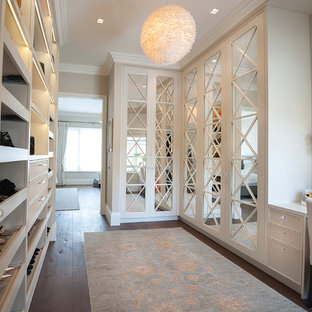 This is an example of a classic gender neutral dressing room in London with recessed-panel cabinets, white cabinets, medium hardwood flooring and brown floors.