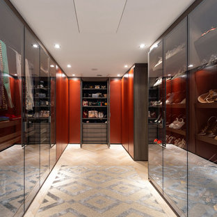 Contemporary gender neutral walk-in wardrobe in Surrey with glass-front cabinets and light hardwood flooring.