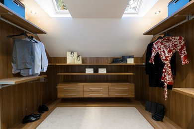 This is an example of a medium sized contemporary gender neutral dressing room in West Midlands with flat-panel cabinets, medium wood cabinets and carpet.