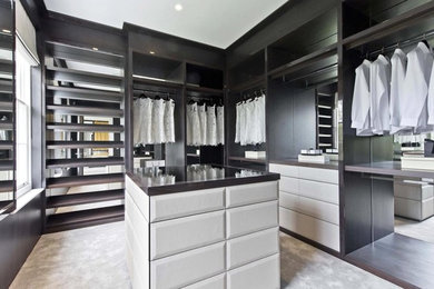 Photo of a medium sized traditional gender neutral walk-in wardrobe in Surrey with raised-panel cabinets, dark wood cabinets, carpet and grey floors.