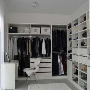 Foto di una piccola cabina armadio unisex minimalista con ante bianche, pavimento in cemento e pavimento grigio