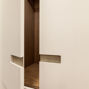 Modern inredning av ett klädskåp för könsneutrala, med luckor med infälld panel och beige skåp