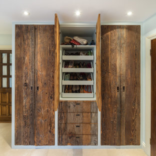 Ejemplo de armario unisex, clásico, de tamaño medio, con armarios con paneles lisos, puertas de armario de madera oscura, moqueta y suelo beige