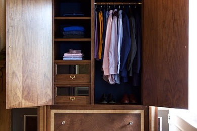 Classic dressing room for men in London with flat-panel cabinets and dark wood cabinets.