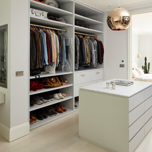 Diseño de vestidor unisex, actual, grande, con armarios con paneles lisos, puertas de armario blancas, suelo de madera clara y suelo beige