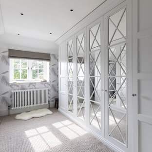 Inspiration for a traditional gender neutral walk-in wardrobe in Dorset with recessed-panel cabinets, white cabinets, carpet and beige floors.