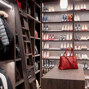 Inspiration for a large classic gender neutral dressing room in London with open cabinets, dark wood cabinets and beige floors.