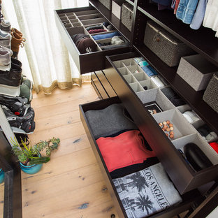 Ispirazione per uno spazio per vestirsi per donna eclettico di medie dimensioni con ante nere, parquet chiaro e pavimento beige