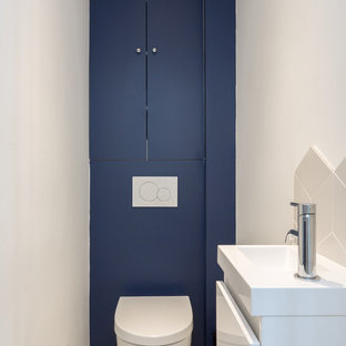 Foto di un piccolo bagno di servizio contemporaneo con ante a filo, ante blu, WC sospeso, piastrelle bianche, piastrelle in ceramica, pareti blu, pavimento in cementine, lavabo sospeso, pavimento giallo e top bianco