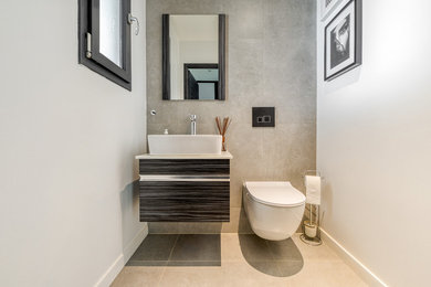 Idée de décoration pour un WC suspendu design avec un carrelage gris et un lavabo posé.