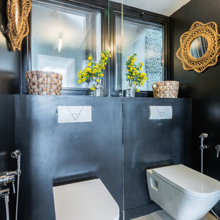 Cette image montre un WC et toilettes bohème avec un WC suspendu, un mur noir, un sol en bois clair et un sol beige.