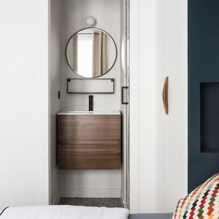 Idée de décoration pour un petit WC et toilettes design avec un placard à porte plane, des portes de placard en bois brun, un mur blanc, un lavabo intégré, un sol gris et un plan de toilette blanc.