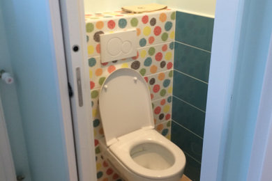 Réalisation d'un petit WC suspendu bohème avec un mur multicolore, un lavabo suspendu et un sol beige.