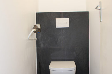 Aménagement d'un WC suspendu contemporain avec un carrelage noir, des carreaux de céramique, un mur blanc, un sol en carrelage de céramique, un plan de toilette en carrelage, un sol noir et un plan de toilette noir.