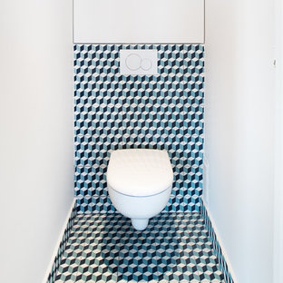 Idée de décoration pour un petit WC et toilettes design avec un WC suspendu, des carreaux de béton, un mur blanc, un sol en carreaux de ciment, un carrelage multicolore et un sol multicolore.