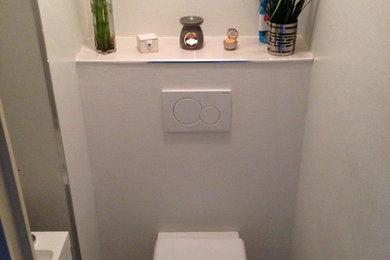 Small contemporary cloakroom in Rennes with a wall mounted toilet, grey tiles, grey walls and a wall-mounted sink.