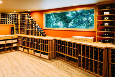 Exemple d'une grande cave à vin éclectique avec parquet clair et des casiers.