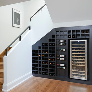 Immagine di una cantina minimal con pavimento in legno massello medio e rastrelliere portabottiglie