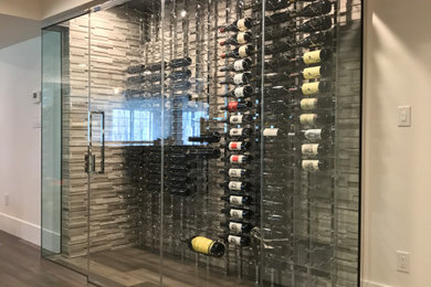 Mid-sized minimalist medium tone wood floor and gray floor wine cellar photo in Philadelphia with display racks