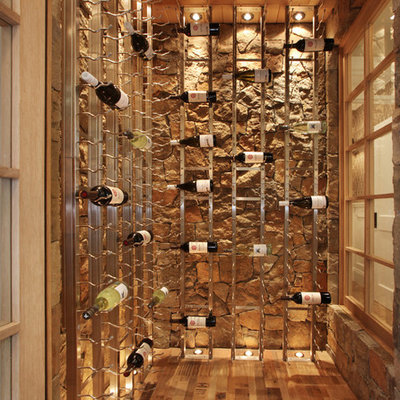 Wine cellar - coastal medium tone wood floor and beige floor wine cellar idea in Orange County with display racks