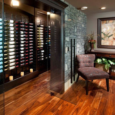 Example of a mid-sized classic medium tone wood floor and orange floor wine cellar design in Calgary with display racks