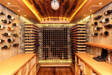 Cette photo montre une cave à vin chic avec un sol en bois brun et des casiers.